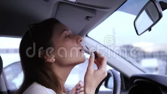 可爱的女司机在车上涂口红上班前化妆唇膏视频的预览图