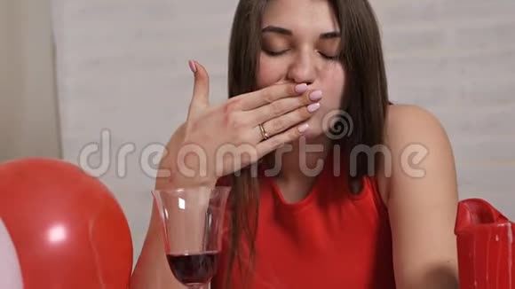 一个穿着红色裙子的漂亮女孩独自在餐桌上喝着一杯酒同时陶醉孤独的情人视频的预览图