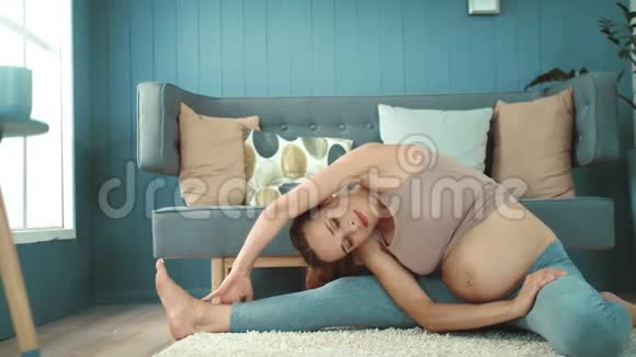 特写微笑孕妇在地板上做瑜伽练习视频的预览图