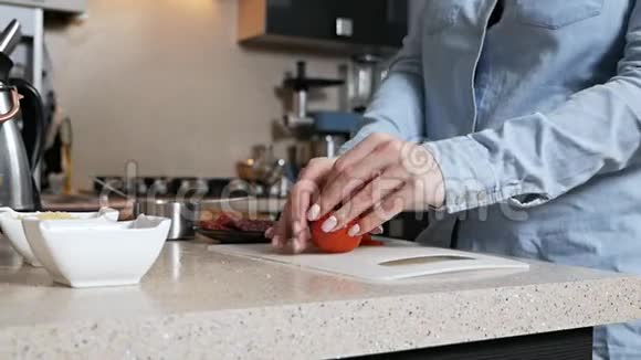 女孩用刀切下一个成熟多汁的西红柿切新鲜蔬菜做披萨视频的预览图