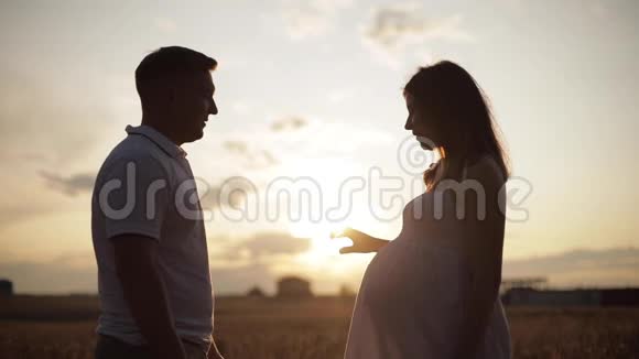 微笑的丈夫和怀孕的妻子摆在明亮的阳光下视频的预览图