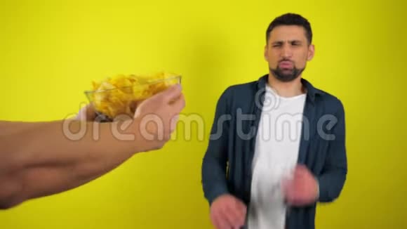 一个穿着蓝衬衫和白T恤的年轻人拒绝了一个装有薯条和垃圾食品的玻璃盘子视频的预览图