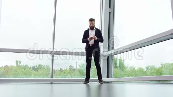 身着便服的布吕内特蓄着胡须的男子正在打电话站在全景窗口附近进行全面的拍摄视频的预览图