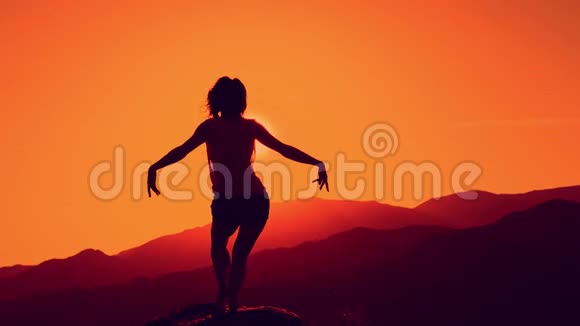 在美丽的落日山背景下跳舞的女性剪影视频的预览图