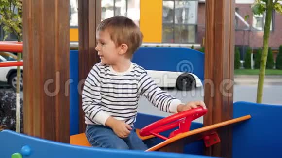 小男孩在公园操场上玩耍时假装司机和旋转方向盘的4k视频视频的预览图