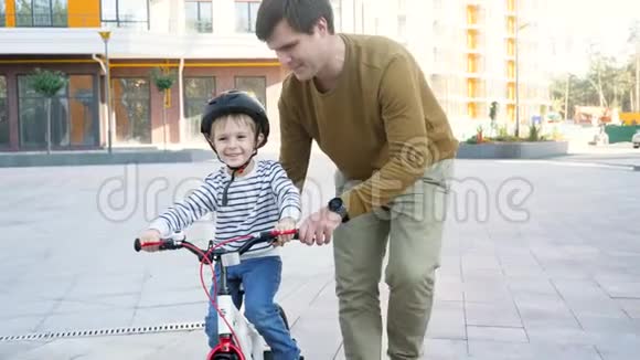 小父亲教小儿子骑自行车上街的4K镜头视频的预览图
