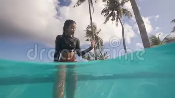 美丽的亚洲女孩泼水坐在热带游泳池的边缘视频的预览图