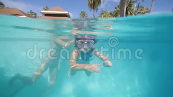 带着游泳面具的小女孩和妈妈一起在游泳池里潜水度假视频的预览图
