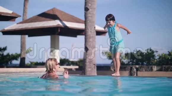 一个单身妈妈和她的小女儿在游泳池里游泳视频的预览图