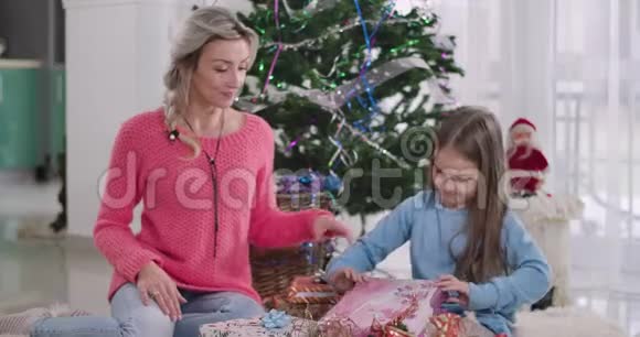 惊讶的白种人女孩打开礼盒妈妈看着她幸福的女人与女儿共度除夕视频的预览图