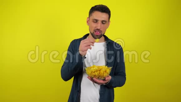 一个穿着蓝衬衫和白T恤的年轻人正在吃一个透明玻璃盘子里的美味薯条并且喜欢它视频的预览图