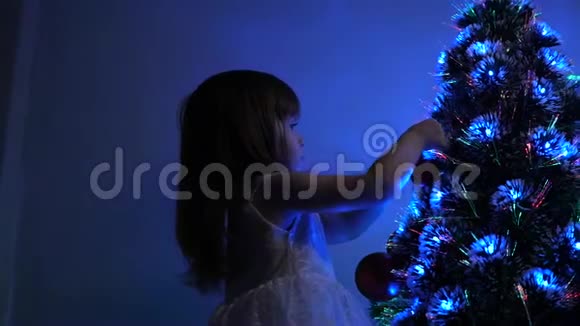 小孩在儿童房的圣诞树旁玩耍孩子们用圣诞球装饰圣诞树女儿视频的预览图