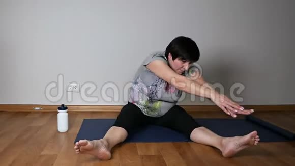 积极主动的老年妇女做热身伸展身体坐在客厅地板上视频的预览图