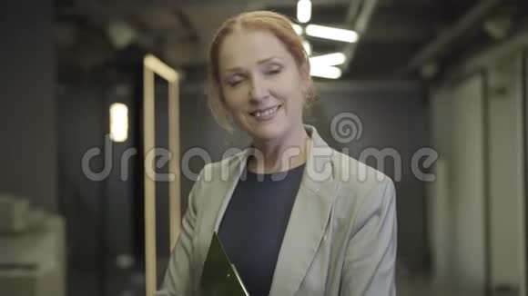 镜头从漂亮的白种人女士的脸移开持有文件夹的中年高加索上班族视频的预览图