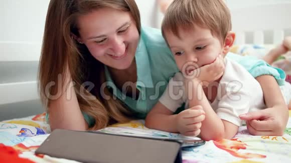 特写4k镜头年轻母亲带着她的小儿子在平板电脑上看视频时微笑和大笑视频的预览图
