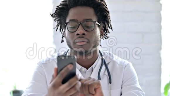 微笑着非洲医生在智能手机上交谈视频的预览图