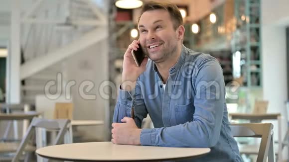 在咖啡厅用智能电话交谈的闲人视频的预览图