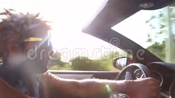 在高速公路上驾驶敞篷车的黑人侧景视频的预览图