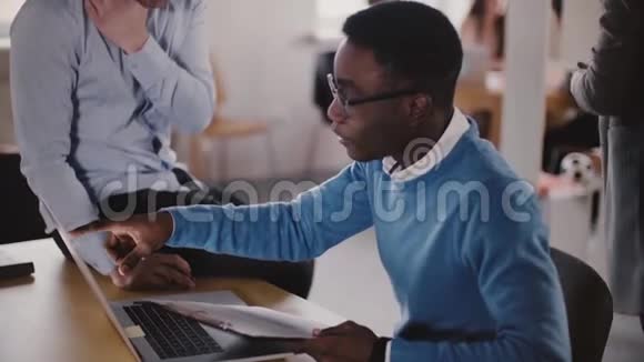 自信的男高管正在帮助他的非裔美国年轻同事进行现代光协同慢动作特写视频的预览图