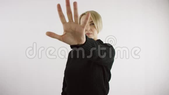 成年白种人愤怒的金发女人在明亮的内部用她的手在白色背景下表现出停止的姿态视频的预览图