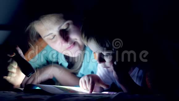 特写4k视频小妈妈晚上和小男孩躺在毯子下看故事书视频的预览图