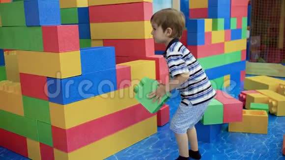 小男孩在商场操场上用五颜六色的大积木搭高塔的视频视频的预览图