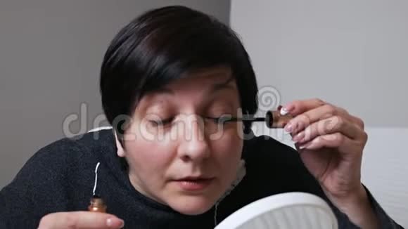 女人画睫毛照镜子走廊房子里的黑色睫毛膏特写视频的预览图