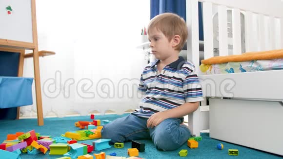 小男孩在房间里玩五颜六色的积木和积木时心烦意乱伤心起来视频的预览图