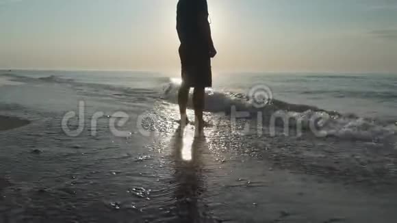剪影一个人在阳光下平静地走在荒芜的海滩上视频的预览图
