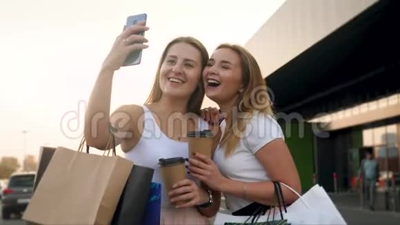 两个快乐的微笑女孩在大商场购物后在智能手机摄像头上自拍的4k特写视频视频的预览图