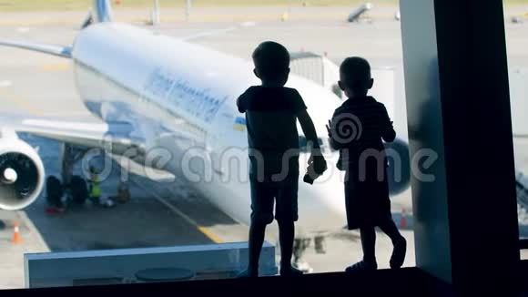 两个小男孩站在机场大窗户附近看大飞机的剪影视频的预览图