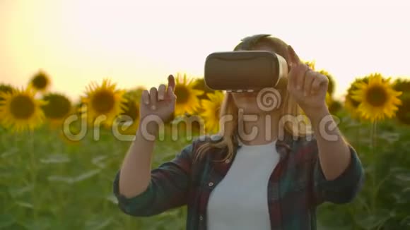 现代女性农民在一个有向日葵的田野使用VR技术模拟应用程序用户界面控制视频的预览图