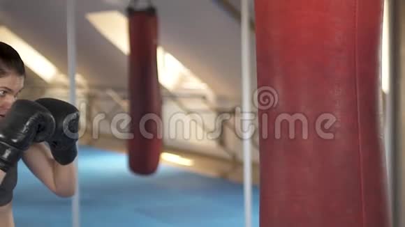 在健身工作室里一位精力充沛肤色浅黑的女子在健身室里用拳击袋训练强壮有力慢动作视频的预览图