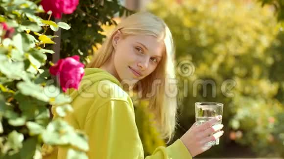 玻璃水的女人的面部肖像美女从绿色公园的玻璃上喝水相当温柔的模特视频的预览图