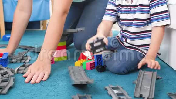 特写4k小男孩和妈妈在客厅地毯上组装玩具铁路的视频视频的预览图