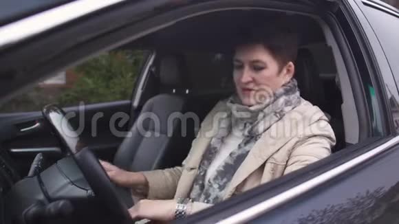 成熟的白种人黑发女人短发坐在司机座位上看着手表妈妈呼唤她视频的预览图