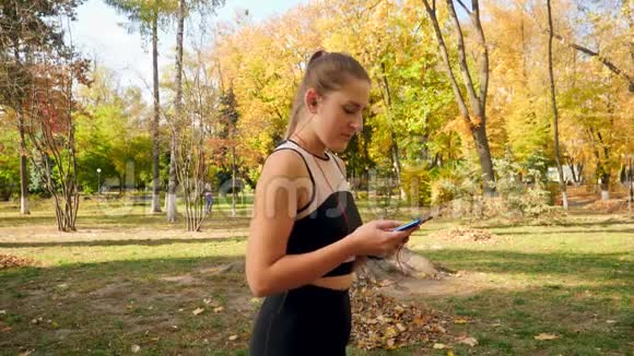 4k视频美丽的年轻女子与马尾辫设置音乐在她的智能手机并开始运行在健身期间视频的预览图