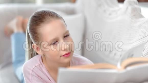 特写脸可爱的小女孩集中阅读有趣的书享受周末舒适的沙发视频的预览图