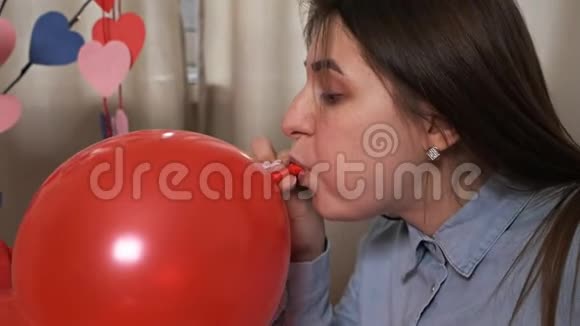 有魅力的年轻女子在家里充气气球为节日情人节准备视频的预览图