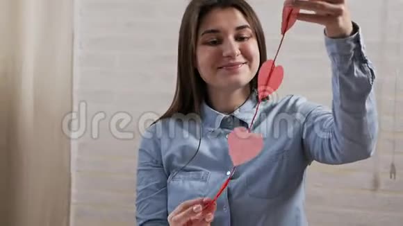 情人节那天一个年轻漂亮的女孩在公寓里准备心脏装饰品视频的预览图