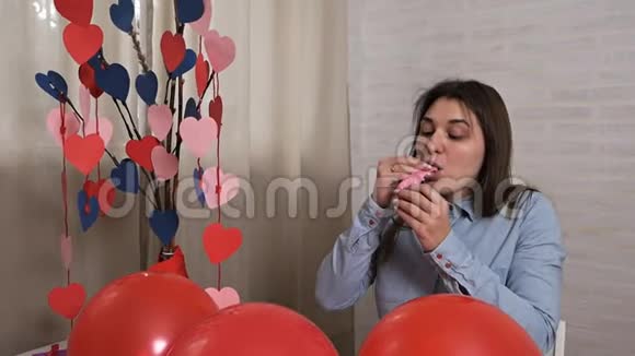 有魅力的年轻女子在家里充气气球为节日情人节准备视频的预览图