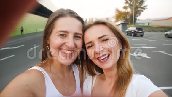 两个美丽的微笑女孩在城市街道的智能手机摄像头上自拍的4kPOV视频视频的预览图