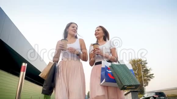 4k低视角视频两个快乐和欢笑的女孩走在城市街道上有很多购物袋和视频的预览图