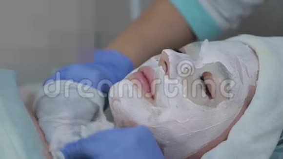 专业美容师女性用湿巾从客户的脸上摘下面具视频的预览图