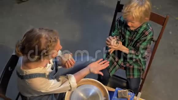 俯视图女人和男孩准备材料工作的陶轮视频的预览图