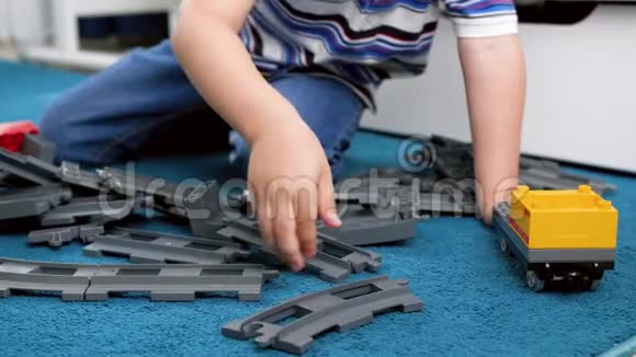4k小男孩在卧室地板上组装玩具铁路的特写镜头视频的预览图