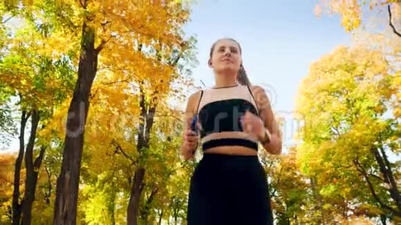 从低角度看4k视频年轻漂亮的女人在阳光明媚的日子在秋天公园跑步视频的预览图