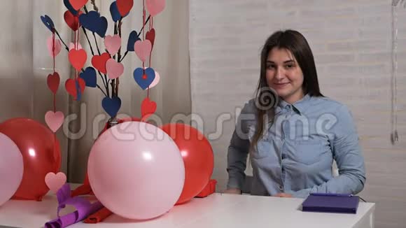 一个微笑的女人拿着一个礼物盒很高兴认为那里情人节概念视频的预览图