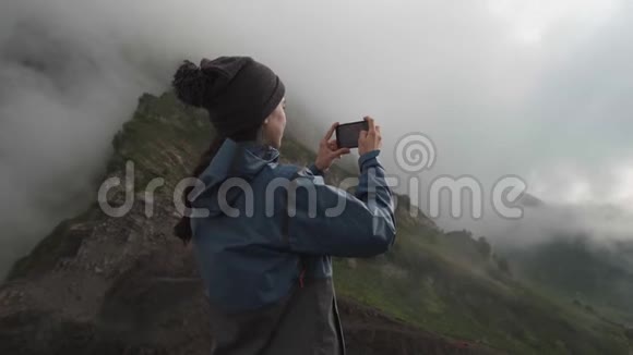 一个远足女孩在山里用智能手机拍照视频的预览图