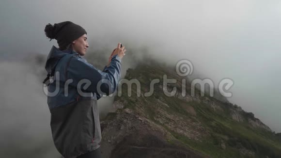 一个远足女孩在山里用智能手机拍照视频的预览图